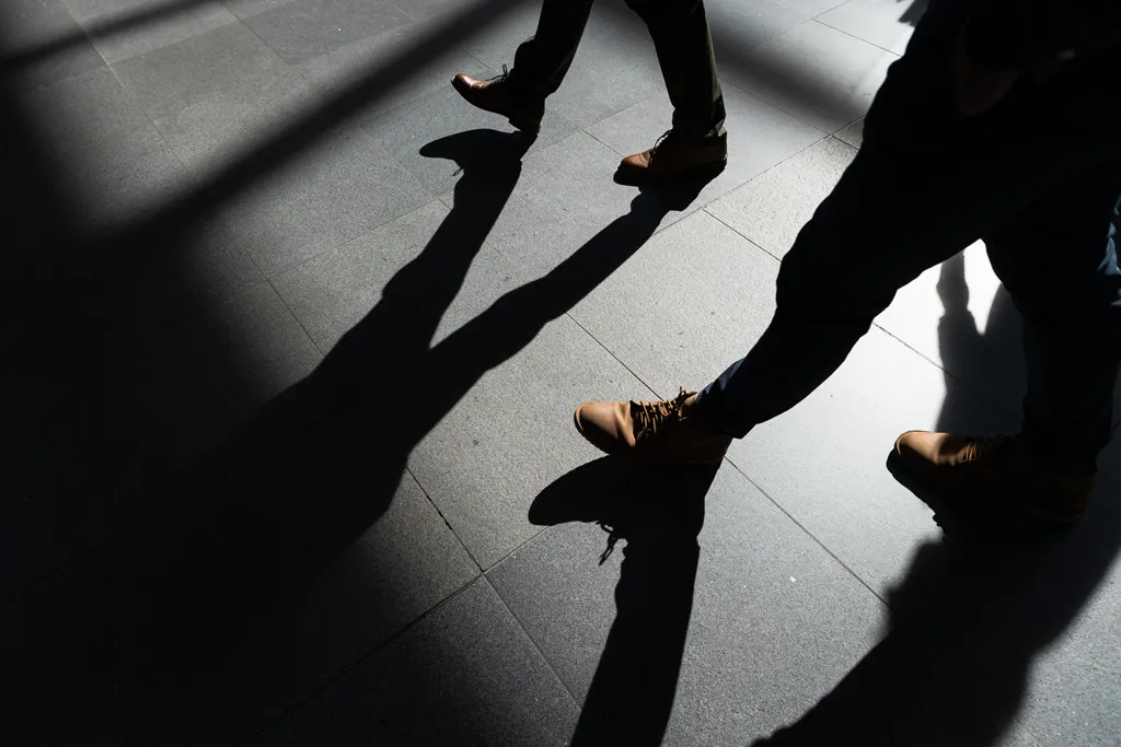 Beine mit hochwertigen Schuhen an den Füßen, die durch einen Lichtstrahl über glatte Betonfliesen laufen. Foto von William Veder · Eventfotografie Berlin | Eventfotograf aus Berlin