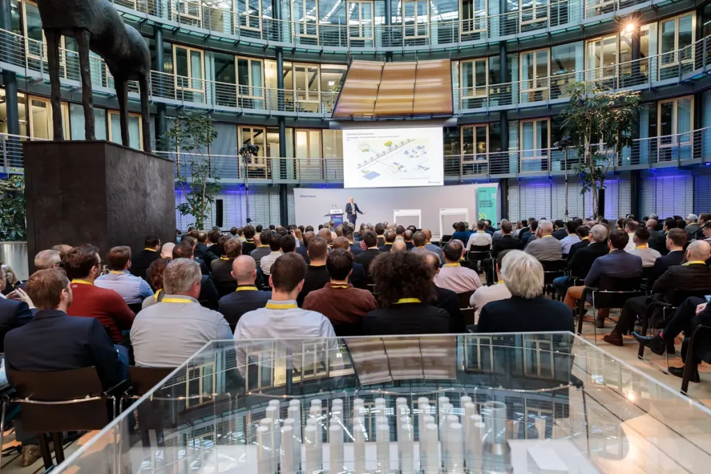 Ein mit Menschen gefülltes Allianz Forum in Berlin während eines Vortrags. William Veder · Eventfotografie — Eventfotograf aus Berlin
